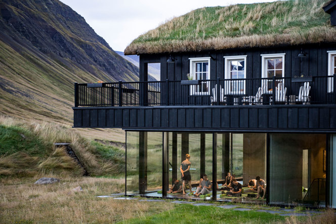 Yoga class seen through the window of a an exterior view of a lodge, with summer iceland landscape